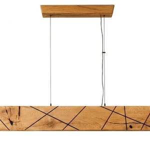May include: A rectangular wooden pendant light with a natural finish. The light has black lines across the wood and hangs from two black cords. The top piece is also wood.