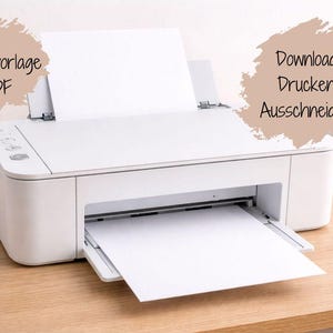 May include: A white inkjet printer with a sheet of blank paper loaded in the top tray and another sheet emerging from the front. Two beige, brush-stroke shaped text boxes are present, containing the German text Druckvorlage PDF and Download Drucken Ausschneiden.