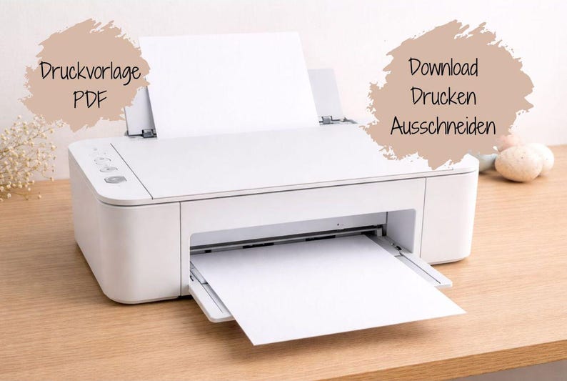 May include: A white inkjet printer with a sheet of blank paper loaded in the top tray and another sheet emerging from the front. Two beige, brush-stroke shaped text boxes are present, containing the German text Druckvorlage PDF and Download Drucken Ausschneiden.