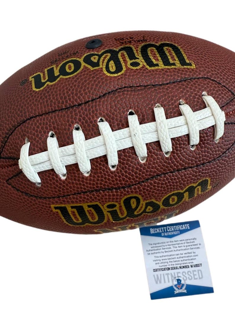 May include: A brown leather Wilson football with white laces. The football has the Wilson logo in gold lettering. A Beckett Certificate of Authenticity is included.