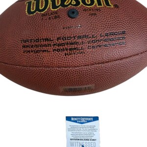 May include: A brown leather Wilson NFL football with white stitching. The football is inflated to 7-9 lbs. The text "Wilson" and "NATIONAL FOOTBALL LEAGUE" are visible. A Beckett Certificate of Authenticity is included.