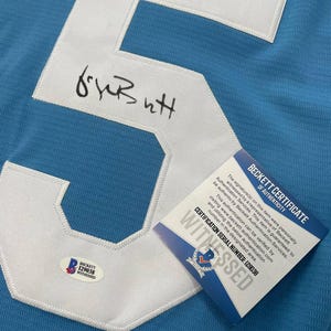 May include: Light blue jersey with a large white number 5 patch. The number is stitched onto the jersey. The jersey has a signature and a Beckett Certificate of Authenticity with the certification serial number 129038.