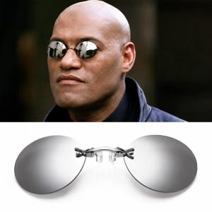 Peut inclure: Lunettes de soleil à clipser sans monture dotées de deux verres circulaires argentés hautement réfléchissants. Les verres sont reliés par un pont métallique central aux détails complexes et de petits plaquettes de nez en silicone transparent.