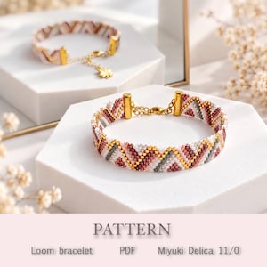 Puede incluir: Dos pulseras de cuentas tejidas con un patrón de chevrón en tonos blanco, rosa, granate y gris con detalles dorados. Cada pulsera tiene terminales de metal dorado, una cadena extensora y un pequeño dije en forma de trébol en el cierre.