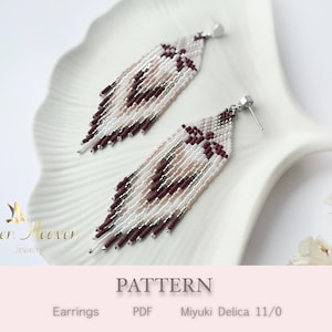 May include: A pair of handmade beaded earrings in a feather design. The earrings feature a combination of white, light pink, and burgundy beads, with silver-colored ear posts. The earrings are displayed on a white, decorative plate.