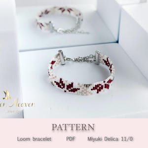 Könnte beinhalten: Ein gewebtes Armband mit einem weißen und roten Muster, das silberfarbene Verschlüsse und eine Kette aufweist. Das Design enthält rote und hellrosa Formen. Das Wort "PATTERN" ist im Bild sichtbar.