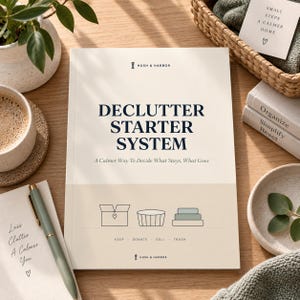 Könnte beinhalten: Ein cremefarbenes Buch mit dem Titel Declutter Starter System und dem Untertitel A Calmer Way To Decide What Stays, What Goes. Das Cover zeigt ein Logo, Strichzeichnungen für keep, donate, sell, trash sowie den Markennamen Hush & Harbor.