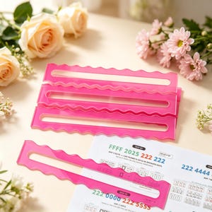 May include: Four bright pink acrylic quilting rulers with wavy edges and a central rectangular cutout. Each ruler features a long slot for marking fabric. One ruler is placed horizontally over a white instruction sheet with printed text.