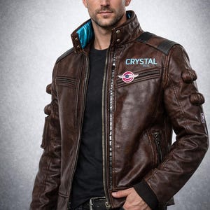 May include: Brown leather jacket with a zip-up front, featuring a blue collar lining and black accents. The jacket has multiple pockets and decorative stitching. The text "CRYSTAL 2036" and a logo are visible on the chest. The bottom of the image reads "CADLEATHERCO CYBERPUNK-INSPIRED Brown Leather Jacket".