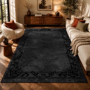 Puede incluir: Una alfombra rectangular grande de color carb&oacute;n con un borde negro adornado. La alfombra est&aacute; colocada en un sal&oacute;n con un sof&aacute; crema, un mueble de madera y un sill&oacute;n blanco. Dimensiones: aproximadamente 240 x 300 cm.