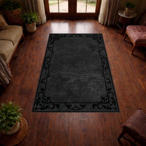 Puede incluir: Una alfombra rectangular negra con un borde decorativo con dise&ntilde;os florales y de volutas. La alfombra est&aacute; colocada sobre un suelo de madera y la habitaci&oacute;n est&aacute; iluminada con luz natural.