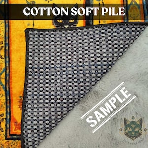 Puede incluir: Una secci&oacute;n de alfombra con un dise&ntilde;o de gato negro, con el texto "COTTON SOFT PILE". La alfombra tiene un borde amarillo y naranja con una ilustraci&oacute;n de gato negro. La parte inferior tiene un patr&oacute;n de cuadros y una textura gris y esponjosa.