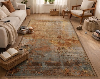 May include: A large rectangular area rug with an abstract design in shades of brown, orange, and blue. The rug has a distressed, vintage look, with a mix of textures and patterns. It is placed on a hardwood floor in a living room setting.