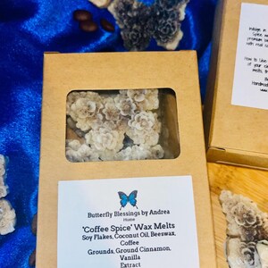 Puede incluir: Una caja de cartón que contiene ceras perfumadas 'Coffee Spice' con una ventana transparente, que presenta un diseño floral. La etiqueta dice 'Butterfly Blessings by Andrea' y enumera ingredientes como copos de soja y café. También se ven formas de mariposas.