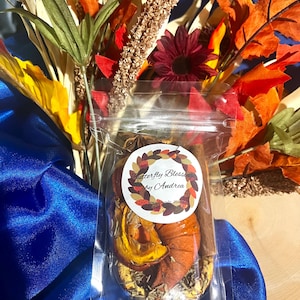 Peut inclure: Un sachet en plastique transparent contenant des tranches d'orange séchées, un bâton de cannelle et de l'anis étoilé. Une étiquette blanche ronde porte une couronne de feuilles d'automne et le texte Butterfly Blessings by Andrea.
