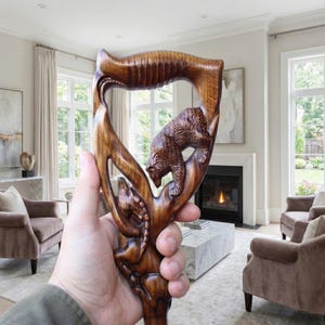 Può includere: Bastone da passeggio in legno intagliato a mano con intagli di orsi e altri animali. Il bastone in legno marrone scuro ha un'impugnatura curva. L'orso è intagliato in modo realistico, con dettagli di pelliccia. Il design è intricato e artistico.