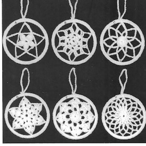 以下が含まれることがあります： 異なるデザインのクロシェのオーナメントが6つあり、それぞれに吊り下げ用のループが付いています。オーナメントは白で、円形をしています。