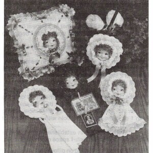 May include: A black and white image titled ANTIQUE DOLLY DOLL featuring a square decorative pillow with a central doll face, three doll heads wearing ruffled bonnets, and one doll wearing a dress. A small rectangular card is also visible.