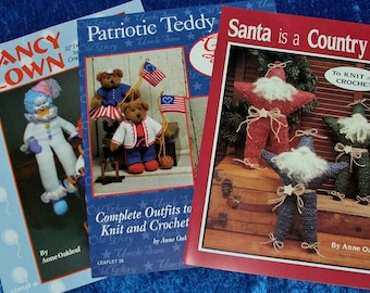 May include: Three craft instruction booklets by Anne Oakleaf. The left booklet features a clown, the centre booklet shows two teddy bears with American flags, and the right booklet displays three star-shaped Santa figures with white beards.