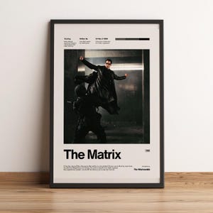 May include: A framed movie poster for The Matrix featuring a central image of a person in a long black coat leaping through the air during a fight scene. The poster includes the title, cast, crew, release date, and a brief plot summary in black text.