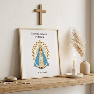 Puede incluir: Una impresión enmarcada con el texto "Nuestra Señora de Luján" y "8 de Mayo" se exhibe en una estantería de madera. La impresión presenta una ilustración religiosa con una combinación de colores azul y dorado. Una cruz de madera cuelga encima de la impresión.