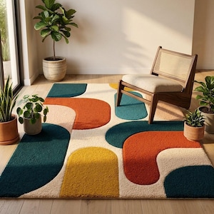 Può includere: Un tappeto colorato con un design astratto. Il tappeto presenta grandi forme curve in verde acqua, arancione, giallo e rosa su uno sfondo bianco sporco. Una sedia in legno e piante in vaso sono visibili sullo sfondo.