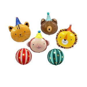 May include: A collection of six foil balloons featuring four animal faces including a tiger, bear, monkey, and lion, each wearing a party hat, alongside two round balloons with vertical stripes and gold star patterns in red and dark green colors.