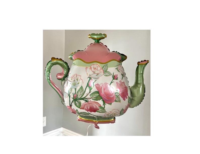 May include: A large, decorative teapot-shaped balloon. The balloon features a floral design with pink roses and green leaves on a white background. The handle and spout are green, and the top is pink and green.
