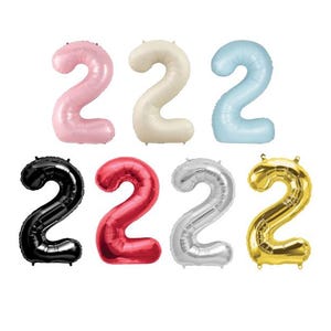 May include: A collection of foil balloons shaped like the number 2 in various colors, including pink, cream, light blue, black, red, silver, and gold. These balloons are suitable for birthday celebrations or other special events.