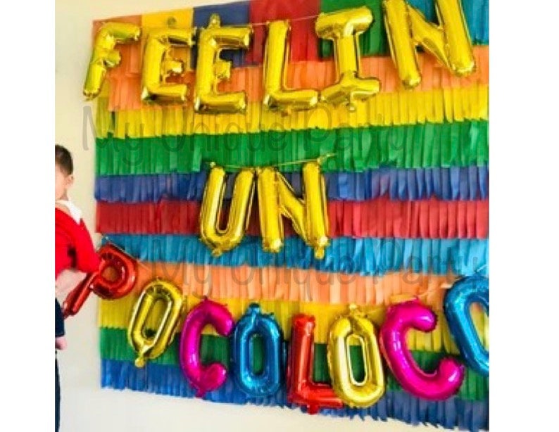 Pu&ograve; includere: Decorazione per feste con palloncini dorati che formano la scritta "FEELIN UN OCOLOC". Lo sfondo &egrave; composto da carta frangiata multicolore, creando un'atmosfera allegra e festosa per celebrare.