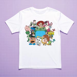 Puede incluir: Camiseta blanca con un gr&aacute;fico colorido de varios personajes de la pel&iacute;cula animada Toy Story. El dise&ntilde;o incluye a Woody, Buzz Lightyear y otros personajes reconocibles. La camiseta tiene mangas cortas y cuello redondo.