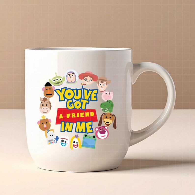 May include: A white ceramic mug featuring a colorful graphic of various cartoon characters arranged in a circle around the text "YOU'VE GOT A FRIEND IN ME" printed in blue and yellow letters on a red background. The mug has a curved handle.