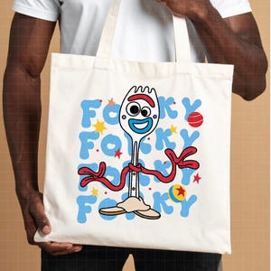 May include: A cream-colored tote bag featuring a cartoon image of Forky from Toy Story. The design includes Forky's face, red arms, and the word "Forky" in blue letters. The bag has a simple, casual design.