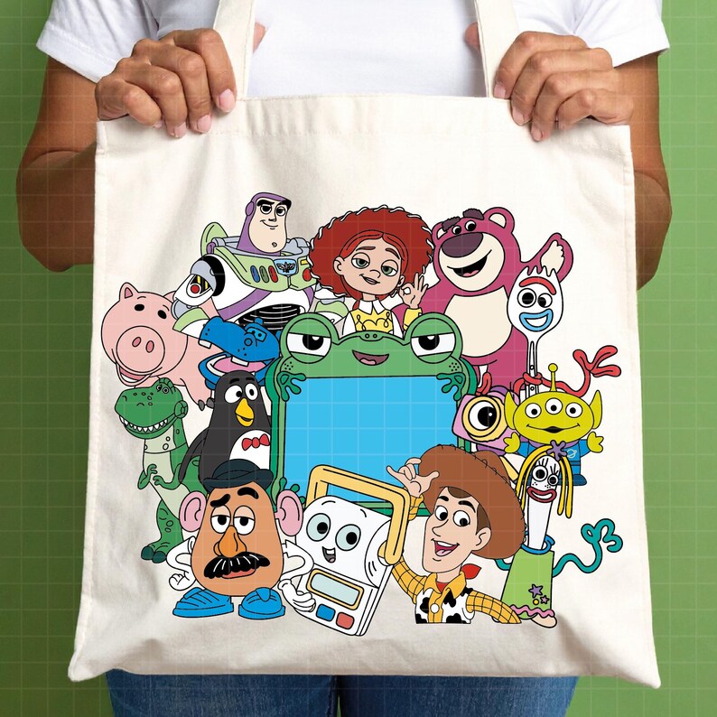Puede incluir: Bolso tote color crema con un gr&aacute;fico colorido de personajes de Toy Story, incluyendo a Woody, Buzz Lightyear y Jessie. El dise&ntilde;o presenta varios personajes de la pel&iacute;cula animada. El bolso es sostenido por una persona.