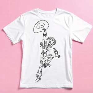 May include: White t-shirt featuring a black outline illustration of a cartoon cowgirl holding a hat. The cowgirl is wearing a cow-print outfit and a hat. The design is centered on the front of the shirt.