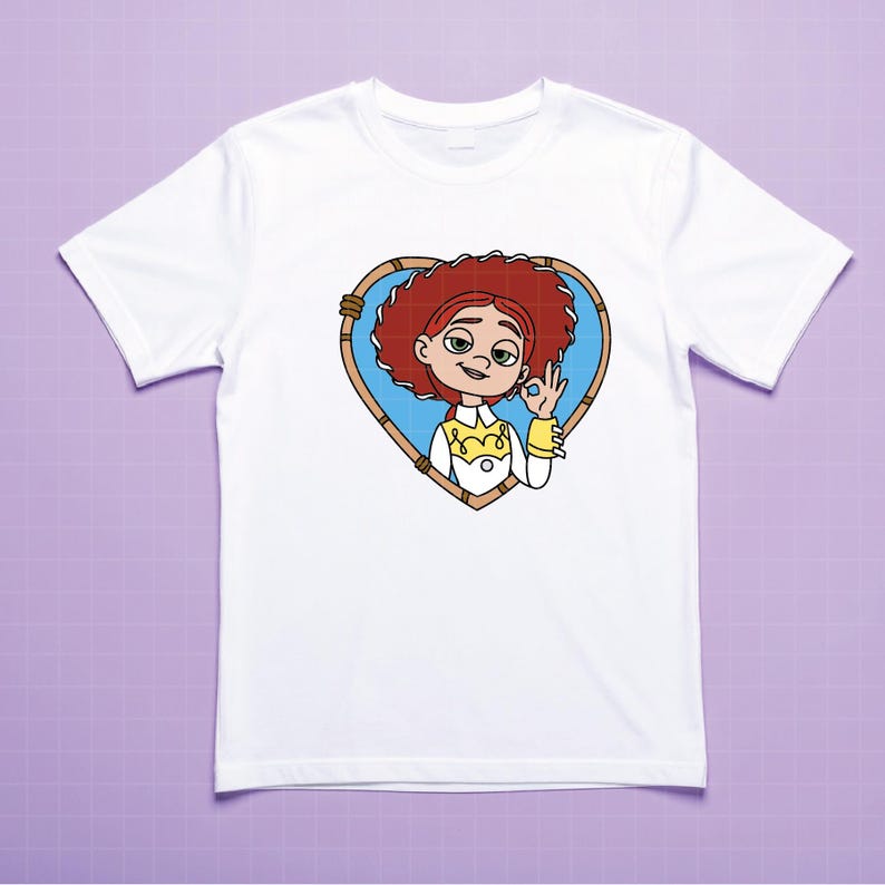K&ouml;nnte beinhalten: Wei&szlig;es T-Shirt mit einer Cartoon-Illustration eines Charakters mit roten Haaren, innerhalb eines herzf&ouml;rmigen Rahmens. Die Figur macht die "Okay"-Handgeste. Das Design ist auf dem T-Shirt zentriert.