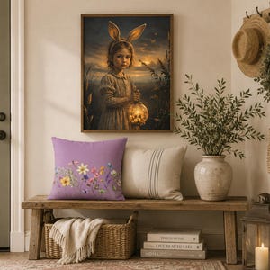 May include: A square purple throw pillow featuring a colorful botanical print of various wildflowers and small insects across the bottom edge, positioned next to a plain beige pillow on a wooden bench beneath a framed wall art print.