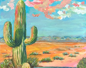 May include: An original oil painting of a desert landscape featuring a large green cactus with a vibrant orange and pink desert floor. The sky is a mix of blue, pink, and white, with a few clouds. The painting evokes a sense of the American Southwest.