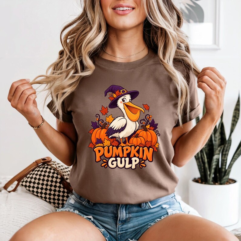 A whimsical illustration of a pelican wearing a purple witch hat, surrounded by orange pumpkins and autumn leaves, with the text PUMPKIN GULP in bold glossy orange letters.