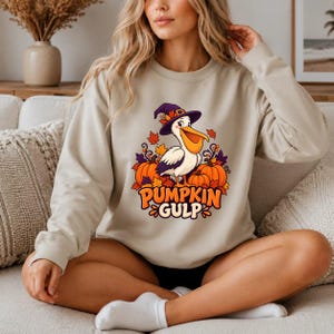 A whimsical illustration of a pelican wearing a purple witch hat, surrounded by orange pumpkins and autumn leaves, with the text PUMPKIN GULP in bold glossy orange letters. — shown on a natural product