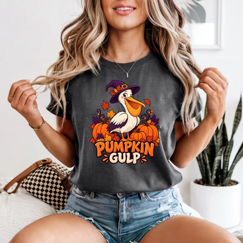 A whimsical illustration of a pelican wearing a purple witch hat, surrounded by orange pumpkins and autumn leaves, with the text PUMPKIN GULP in bold glossy orange letters.