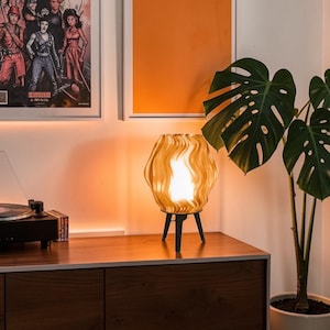 Könnte beinhalten: Eine weiße Keramik-Tasse mit schwarzem Henkel und dem Text "But First, Coffee" in schwarzer, handschriftlicher Schrift. Die Tasse steht auf einer weißen Oberfläche.