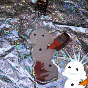 Puede incluir: Un llavero acr&iacute;lico transparente con un dise&ntilde;o de mu&ntilde;eco de nieve con una botella de cerveza. El mu&ntilde;eco de nieve tiene un cuerpo blanco, puntos negros y una cara sonriente. El llavero incluye un mosquet&oacute;n y el texto "FROSTCORPSCLUB" en azul.
