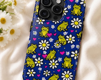 Puede incluir: Una funda de smartphone azul oscuro con un patrón repetitivo de ranas de color verde claro, margaritas blancas con centro amarillo y pequeños corazones rosas. La funda tiene un recorte para un sistema de triple cámara en la parte superior.