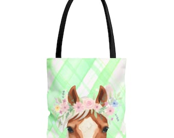 Puede incluir: Un bolso tote con la cabeza de un caballo marrón con una mancha blanca en la frente, luciendo una corona de flores rosas, azules y amarillas. El fondo presenta un patrón de cuadros diagonales en verde claro y blanco con asas negras.