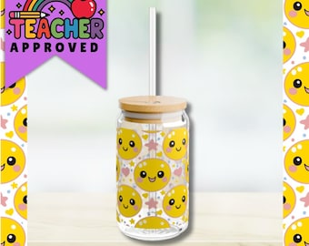 Puede incluir: Un vaso de vidrio transparente con tapa de bambú y pajita transparente. El vaso está decorado con caras sonrientes amarillas y estrellas rosas. Las palabras "TEACHER APPROVED" están impresas sobre un fondo morado con un arcoíris y una manzana.