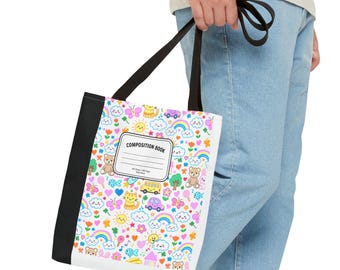 Puede incluir: Bolso tote blanco con un estampado colorido de osos de dibujos animados, arcoíris, coches y corazones. El bolso tiene lomo y asas negras, y presenta el texto "COMPOSITION BOOK" en la parte delantera.