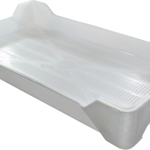 May include: A white plastic tray with a raised grid pattern on the bottom. The tray has a rectangular shape with rounded corners and slightly raised edges.