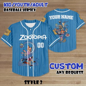 Puede incluir: Una camiseta de b&eacute;isbol azul claro con rayas blancas, con la palabra "ZOOTOPIA" y el n&uacute;mero "00" en la parte delantera. La parte trasera tiene "YOUR NAME" y gr&aacute;ficos de personajes. La camiseta est&aacute; etiquetada como "STYLE 2".