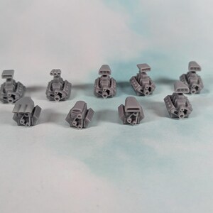 May include: A collection of ten small, gray miniature engine models. Each model has intricate details, including exhaust pipes and air intakes. The engines are arranged on a light blue and white surface.